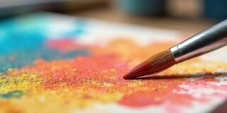 Pinsel mit bunten Farben auf einer Pallette.