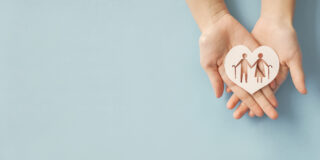 Zwei Hände halten ein Herz mit Symbolen: Senioren, die auf Hilfe angewiesen sind.