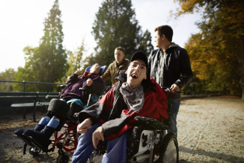Junge Menschen - darunter Rollstuhlfahrer - genießen einen Ausflug in herbstlicher Landschaft.